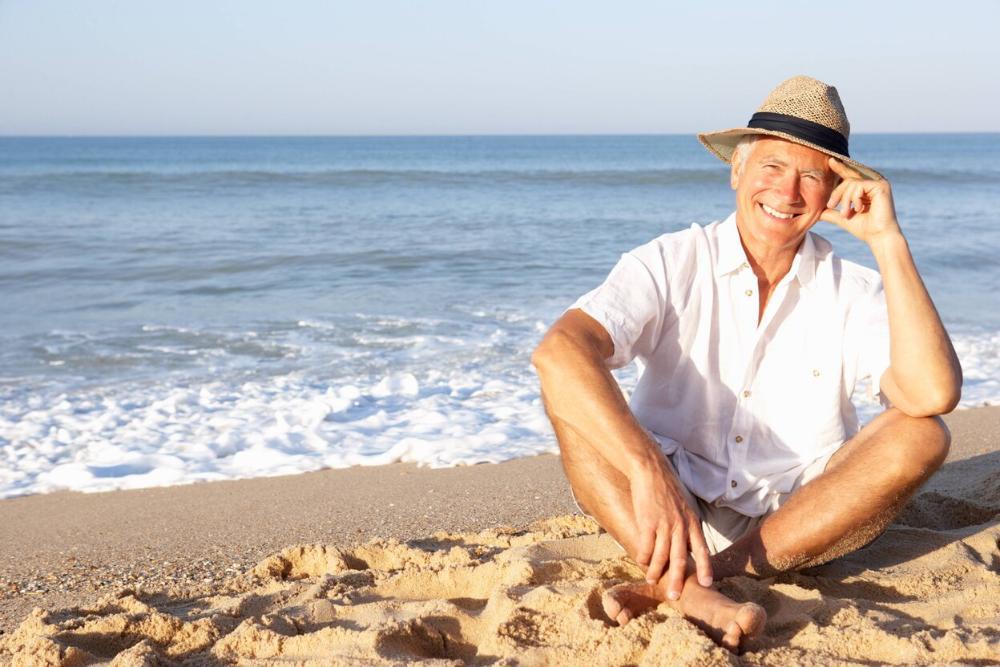 man sitting on beach smiling | dentures royal palm beach, FL